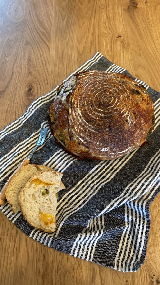 Jalapeno cheddar sourdough with spiral scoring, sliced to show melted cheddar inside